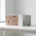 Architectonisch schaalmodel transformatie vs nieuwbouw met rolstoel, half baksteen-hout half wit beton-glas op witte tafel