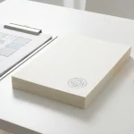 Stap certificeringsdocumenten met stempel en bouwtekening op klembord op witte desk, minimalistisch zorggebouw ontwerp