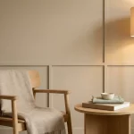 Minimalistische, dementievriendelijke woonkamerhoek met armstoel, bijzettafel met boek en lamp in warm, rustig licht