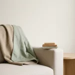 Fauteuil met tweezijdige deken van wol en katoen, materiaalstalen op armleuning, minimalistisch interieur in zacht ochtendlicht