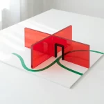 Minimalistisch 3D vloerplan met rode brandcompartimenten, groene route en zwarte deur op witte tafel, daglicht links