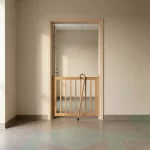 Wandelstok leunt tegen veiligheidspoort in open deur van rustige verpleeghuisgang, zacht ochtendlicht en minimalistisch design