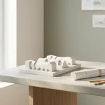 Witte schaalmodel woonwijk op architectenbureau naast opgerolde bouwtekening en houten passer, in minimalistische studio