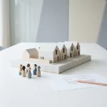 Architectuur maquette van rijtjeshuizen met houten pionnen in overleg, siteplan en potlood op witte tafel in daglicht